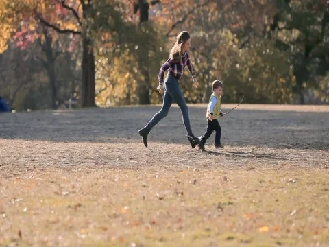 Young mother having fun with her kid son in autumn park, playing with leaves Stock Footage 74006346