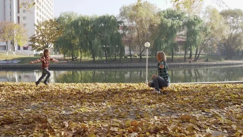 Young mother having fun with her son in autumn park at sunny day Stockbeeldmateriaal 97096389