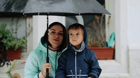 Young mother with her son hide under an umbrella during the rain Stock Footage 120629611