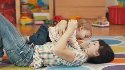 Young Mother Holding Her little baby son in the room lying on the floor. Stock Footage