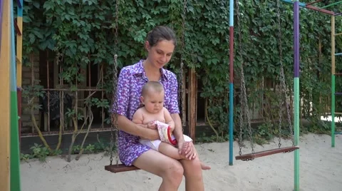 Young Mother keeps a small child in her arms swinging on a swing Stock Footage 67407707