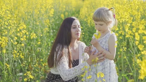 A young mother with a little daughter in a rapeseed field. Slow motion Stock Footage