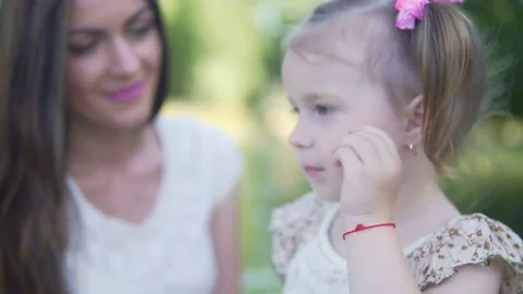 A young mother is looking at her little daughter lovingly. Close-up Stock Footage