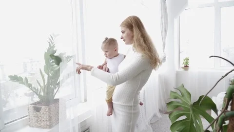 Young mother looking at the window with her small baby boy Stock Footage 73633688