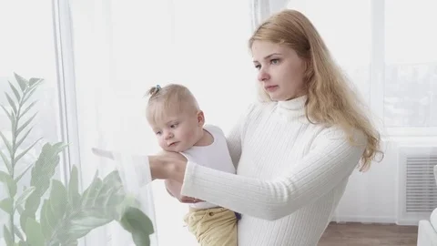 Young mother looking at the window with her small baby boy, closeup Stock Footage 73633851