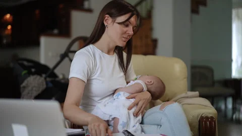 Young mother multitasking holding a sleeping baby while working from home Stock-Footage 331302566