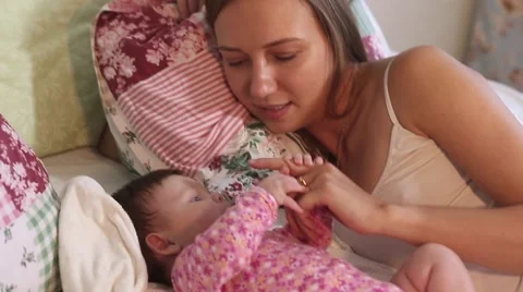 Young mother playing with her little baby on the bed - indoors Stock Footage