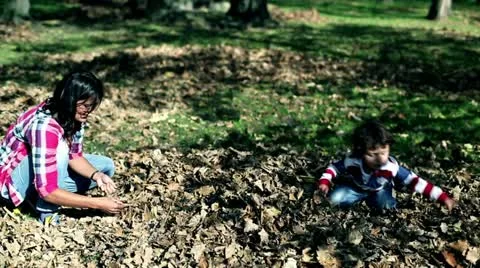 Young mother playing with her son in autumn park, steadycam Stock Footage