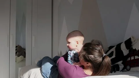 a young mother plays in bed with a young... | Stock Video