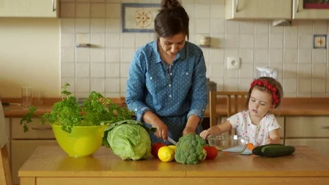 A young mother is preparing dinner in the kitchen. She cuts the carrots. A Stock Footage
