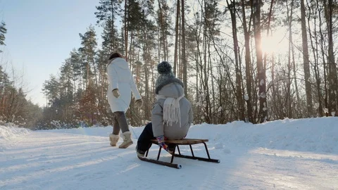 Young mother rolls her son on sledding Stock Footage 101417587