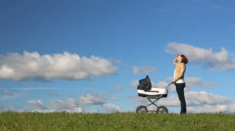 Young mother running while pushing a stroller on meadow Stock Footage 67560335