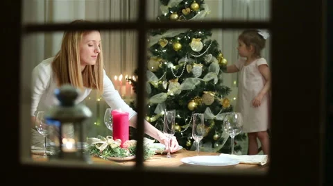 Young mother server festive table, her little daughter decorates Christmas tree. Video stock 68539171
