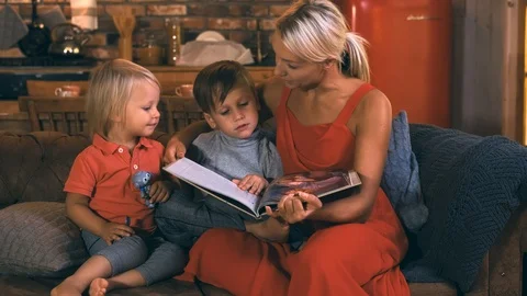 A young mother sits on a sofa with two children, boys, in the background of the Stock Footage 118487310