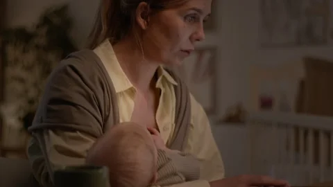 Young Mother Sitting at Table Working on Laptop while Baby Sleeping in Sling Stock Footage 281258833
