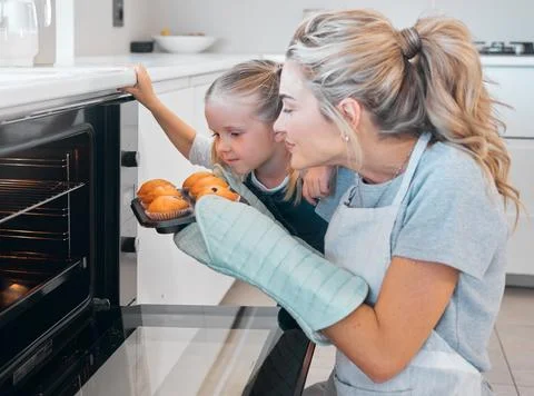 Young mother smelling a tray of fresh baked muffins. Caucasian woman sniffing a Stock Photos