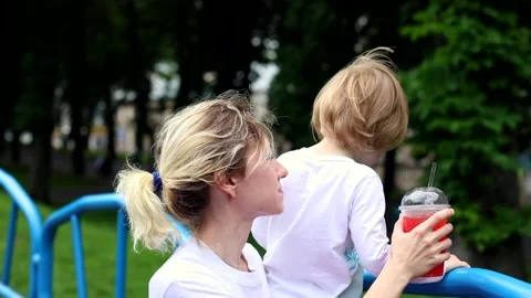 Young mother spending time talking with little son resting on branch. City urban Stock Footage 134467396