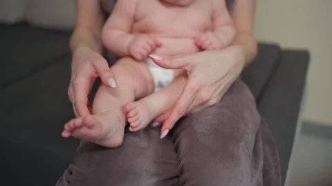 A young mother spends time with her baby, playing with her legs 库存影片 237029231