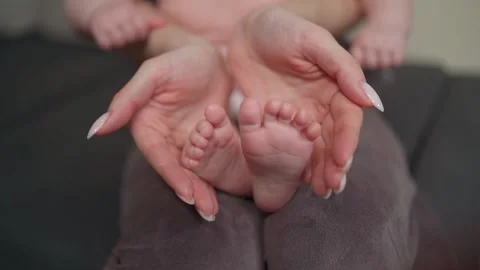 A young mother spends time with her child, gently holding her tiny legs Vidéo 237029348