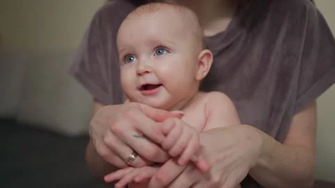 A young mother spends time with her cute baby, gently holding her hands. 库存影片 237029363