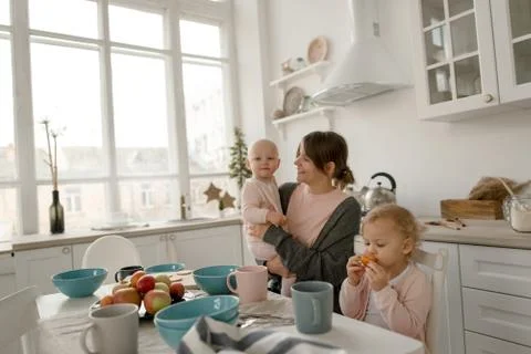 A young mother spends time with her little daughters at home. Stock Photos