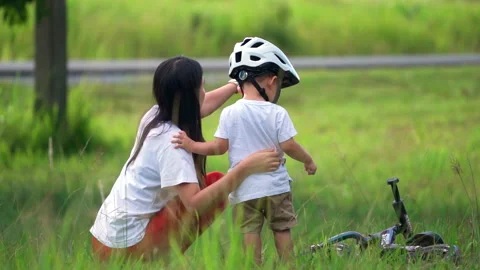 Young mother teaching her son to ride the bicycle at natural park. Stock Footage 233279286
