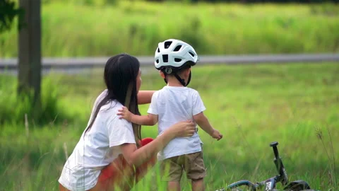 Young mother teaching her son to ride the bicycle at natural park. Stock Footage 233279339