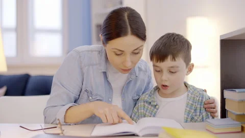 Young mother teaching son to read at home, helping to do homework, dyslexia Vídeo Stock 149244229