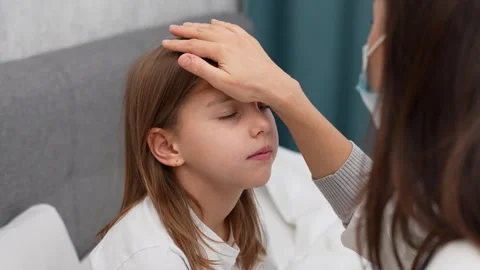 Young mother touching daughter's forehead. Stock Footage 256763789