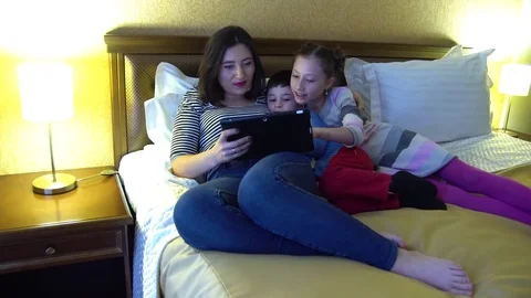 A young mother with two children lying in hotel in bed. Stock Footage 74283653