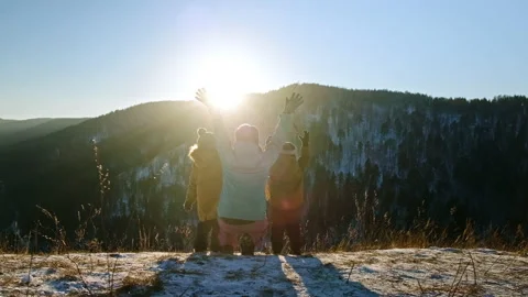 A young mother with two sons joyfully raise their hands standing on top of a Video stock 168763130