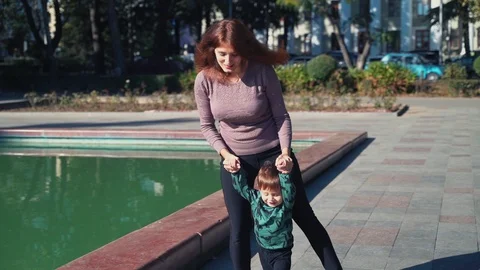 A young mother with a two year old son walks in the city near the pond. Sunny Stock Footage 118674652