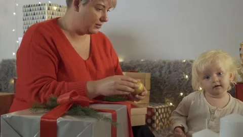 Young mother tying bow on Christmas present while her daughter helping to her Stock Footage 139632553
