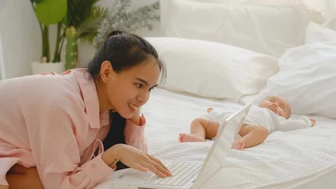 Young mother use laptop to work at home and also take care her newborn Stock-Footage 127528512