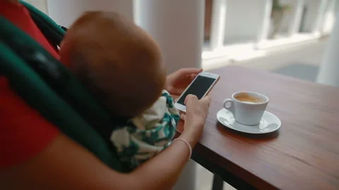 Young mother uses a smartphone while sitting in a cafe Stock Footage 105641719
