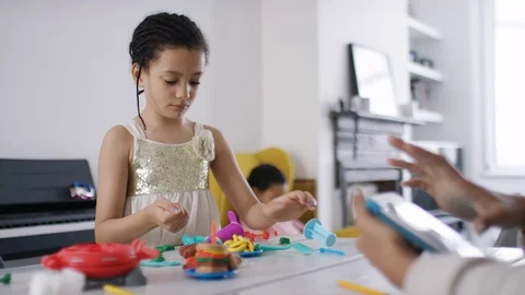 Young mother using a digital tablet as her child plays on the table Stock Footage 81631450