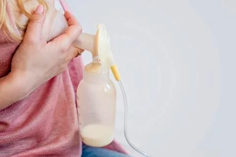 Young mother is using single electric breast milk pump and pumping breast mil Foto stock