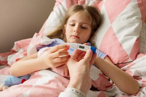 Young mother using a thermometer to temperature with her little daughter Stock Photos