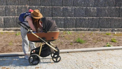 A young mother walking and try to get her baby out of the stroller. Family Stock Footage 116500935