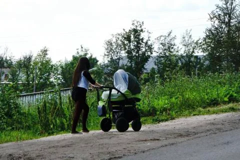 Young mother walking a stroller in the park Stock Photos