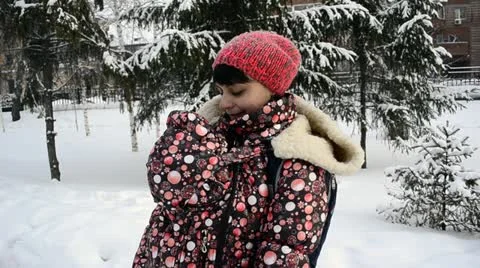Young mother walking in a winter park with a baby in a sling-jacket Stock Footage