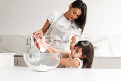 Young mother wearing apron cooking pastry with her little daughter together, Stock Photos