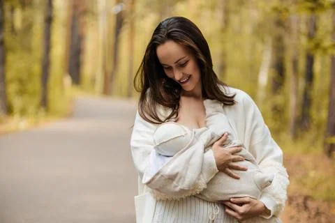 Young mother in white jacket, woman with newborn baby in arms in forest, Park Stock Photos