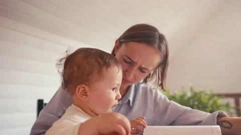 A young mother is working at home using computer while she's taking care of her Vídeos de archivo 164481070