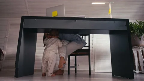 A young mother is working at home using computer while she's taking care of her 스톡 동영상 164853454
