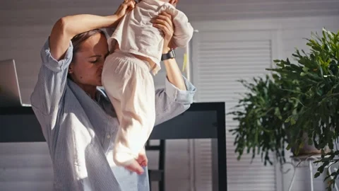 A young mother is working at home using computer while she's taking care of her Stock Footage 164853602