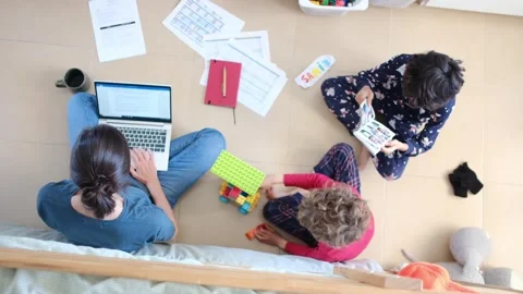 Young mother working at home while taking care of her sons Vídeos de archivo 270483600