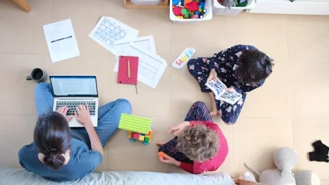 Young mother working at home while taking care of her sons Vídeos de archivo 270483616