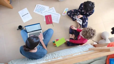 Young mother working at home while taking care of her sons Vídeos de archivo 270483618