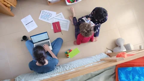 Young mother working at home while taking care of her sons Vídeos de archivo 270483625
